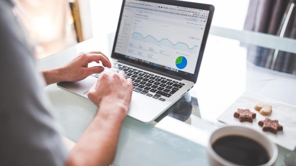 Person working on a laptop showing an analytics dashboard with growth charts