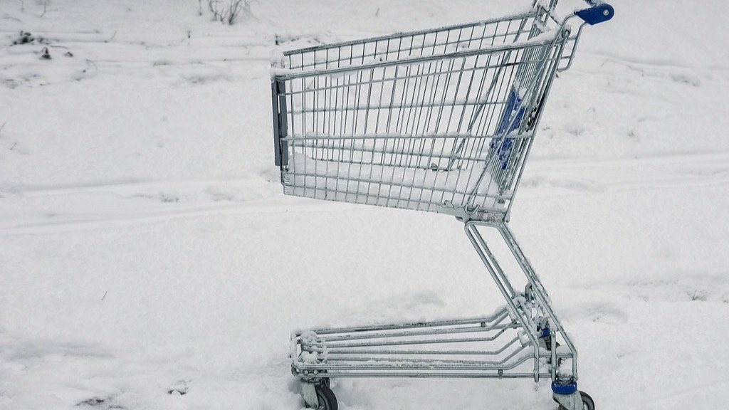 Empty shopping cart left alone in the snow, representing an abandoned cart
