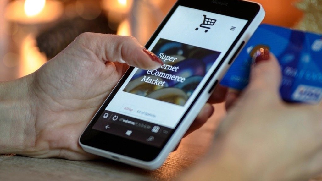 Shopper searching an online store on a smartphone while holding a payment card