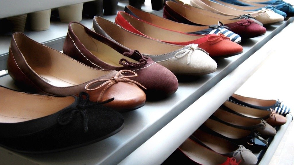 Rows of shoes in different colors and styles neatly arranged on store shelves