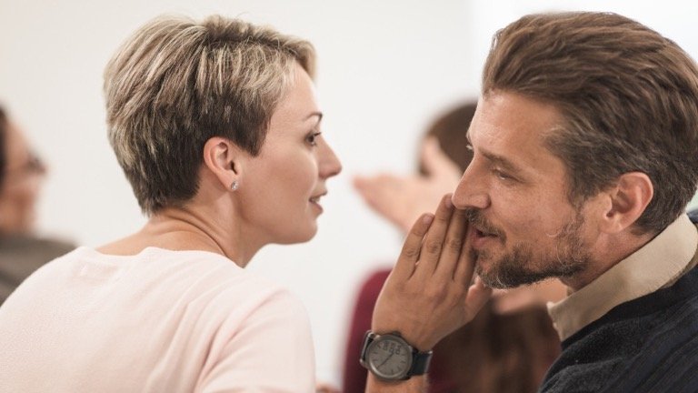 Woman listening as a man whispers a recommendation, representing word-of-mouth affiliate referrals