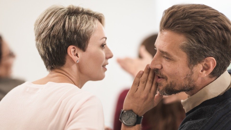 Woman listening as a man whispers a recommendation, representing word-of-mouth affiliate referrals