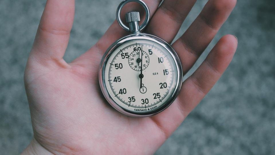Hand holding a silver stopwatch, representing a sale countdown timer on a WooCommerce product