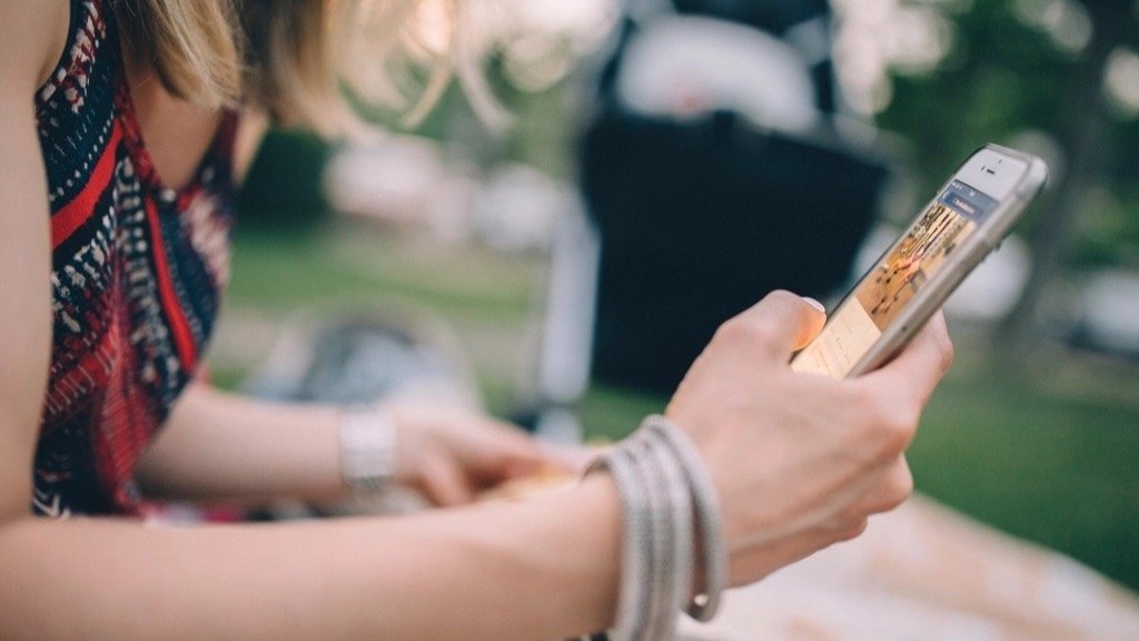 Woman scrolling through products on her smartphone while sitting outdoors