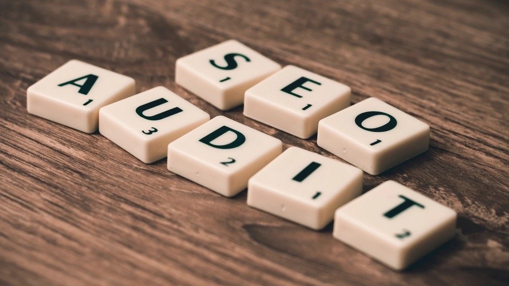 Wooden letter tiles spelling SEO AUDIT on a dark wooden table